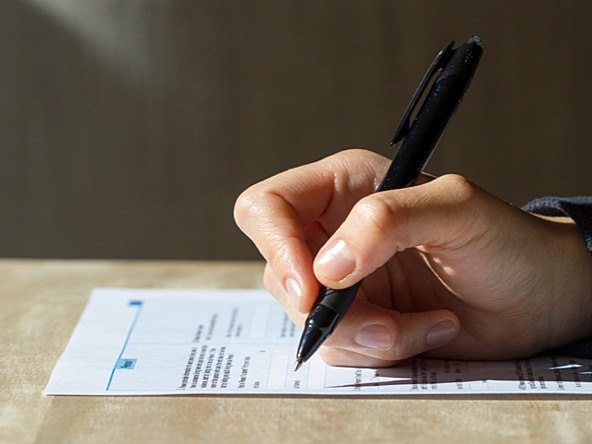 person's hand completing census questionnaire using pen